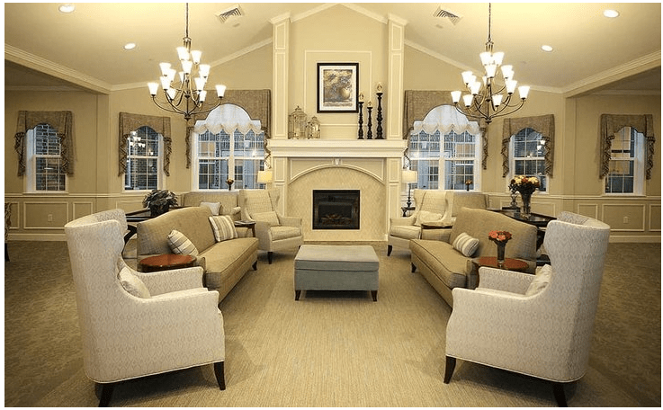 A cozy and elegant living room featuring a central fireplace, multiple sofas, large windows, and chandeliers.