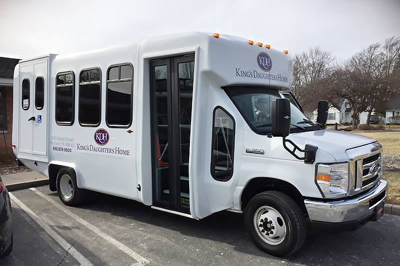 A white shuttle bus parked in a lot, used for passenger transportation.