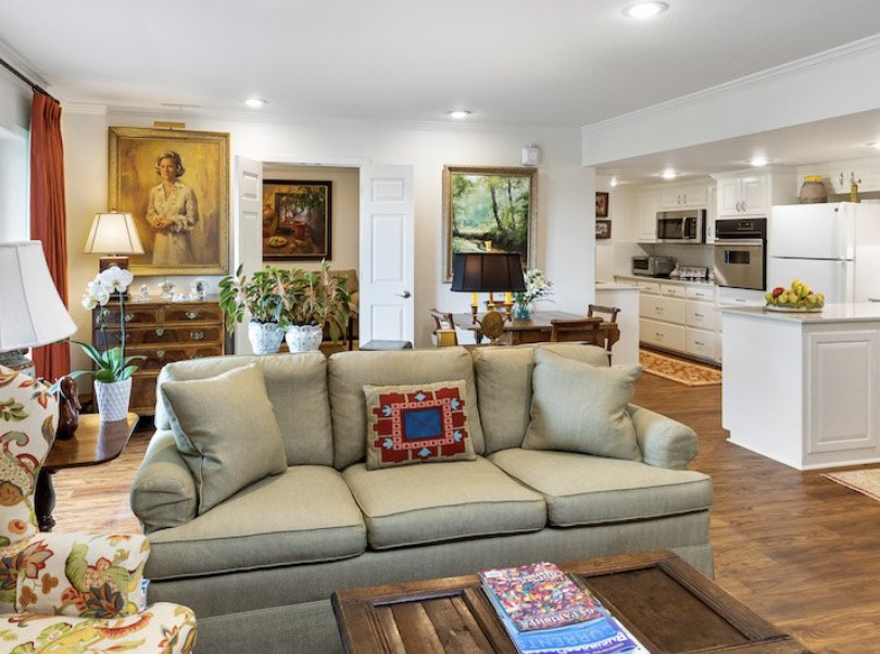 A modern living room with an open kitchen design, featuring stylish artwork and cozy furniture.