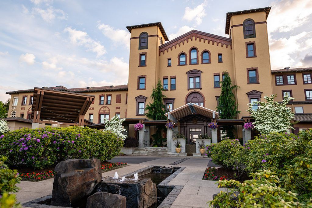 A beautiful hotel building with charming architecture, surrounded by a landscaped garden and pathway.