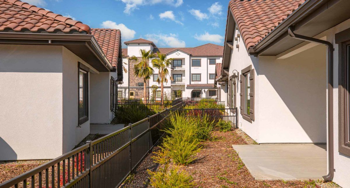 A scenic view of modern residential apartments with well-maintained landscaping and a clear blue sky.