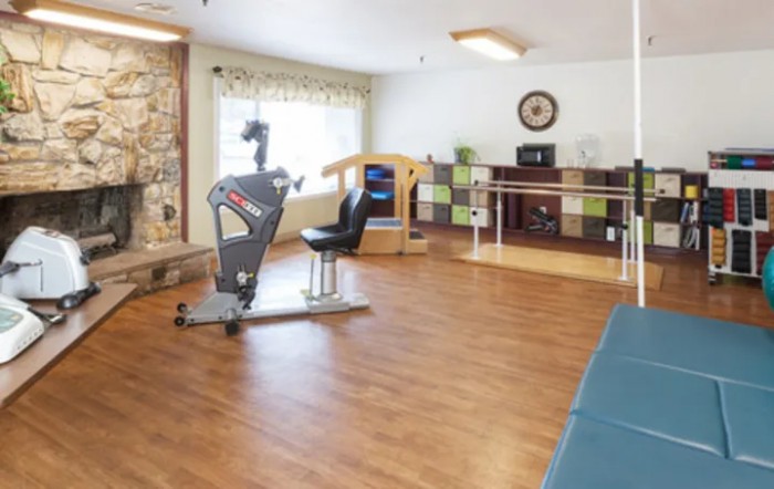 A well-lit fitness room with an exercise bike and other gym equipment for rehabilitation purposes.