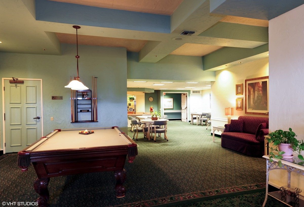 A cozy indoor game room featuring a pool table, seating areas, and ambient lighting.