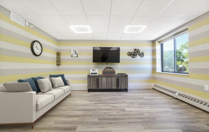 A modern living room with a striped wall, featuring a TV and cozy seating.