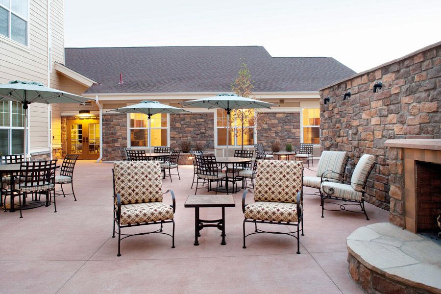 A cozy outdoor patio with stylish seating and umbrellas, set against a backdrop of brick walls and evening lights.