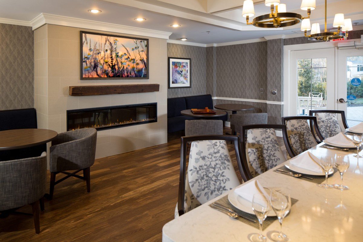 A modern dining room with elegant dcor, featuring a fireplace, artwork on the walls, and a beautifully set table.