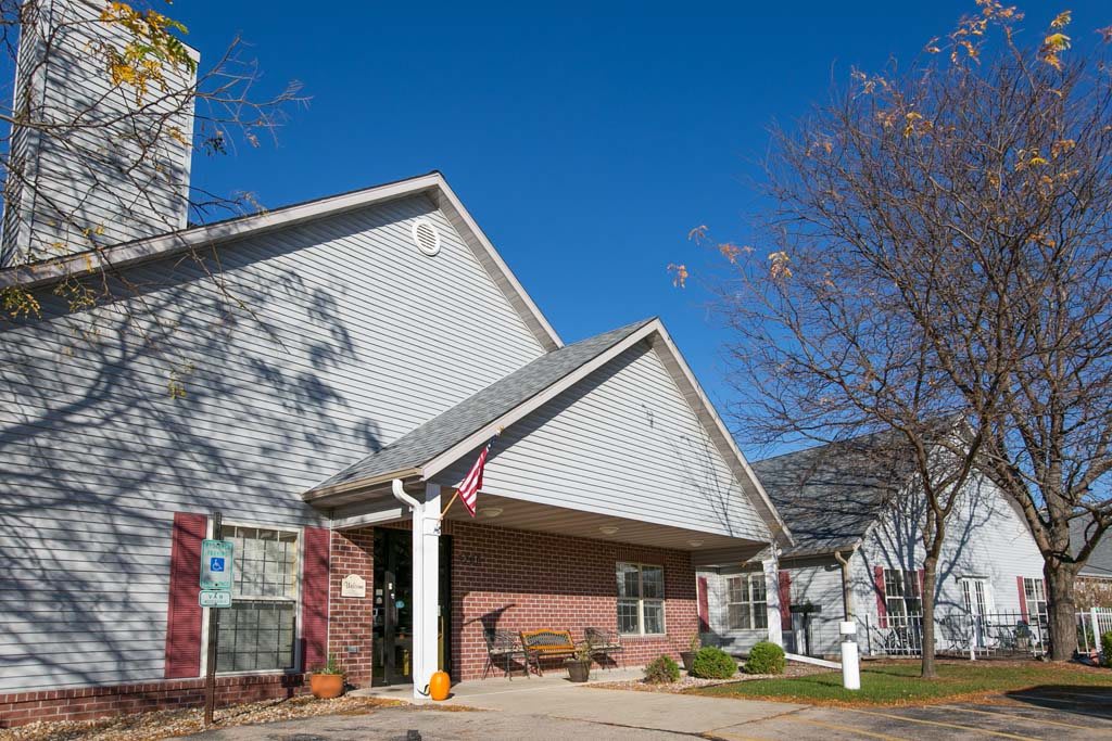 A suburban house with a gabled roof under a clear blue sky, surrounded by trees with autumn leaves.