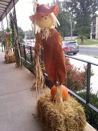 A festive scarecrow stands next to hay bales and a pumpkin, celebrating the autumn season.
