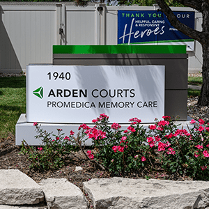 Sign for Arden Courts ProMedica Memory Care surrounded by flowers.