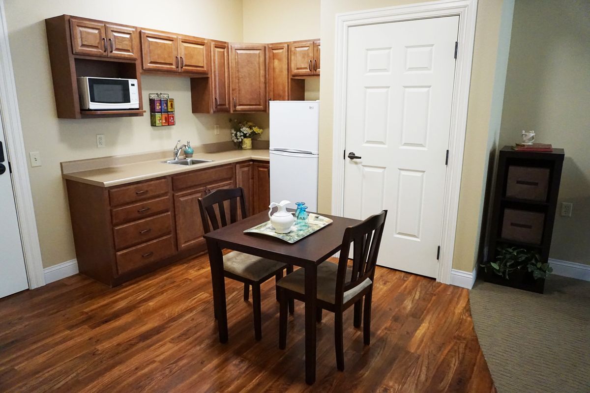 A cozy kitchen with wooden cabinets, a small dining table with two chairs, and modern appliances.