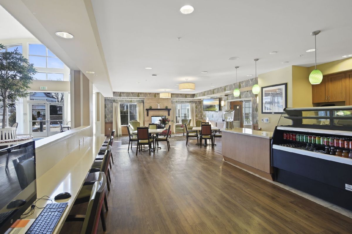 A modern dining area with wood flooring, featuring tables and chairs under bright lighting.