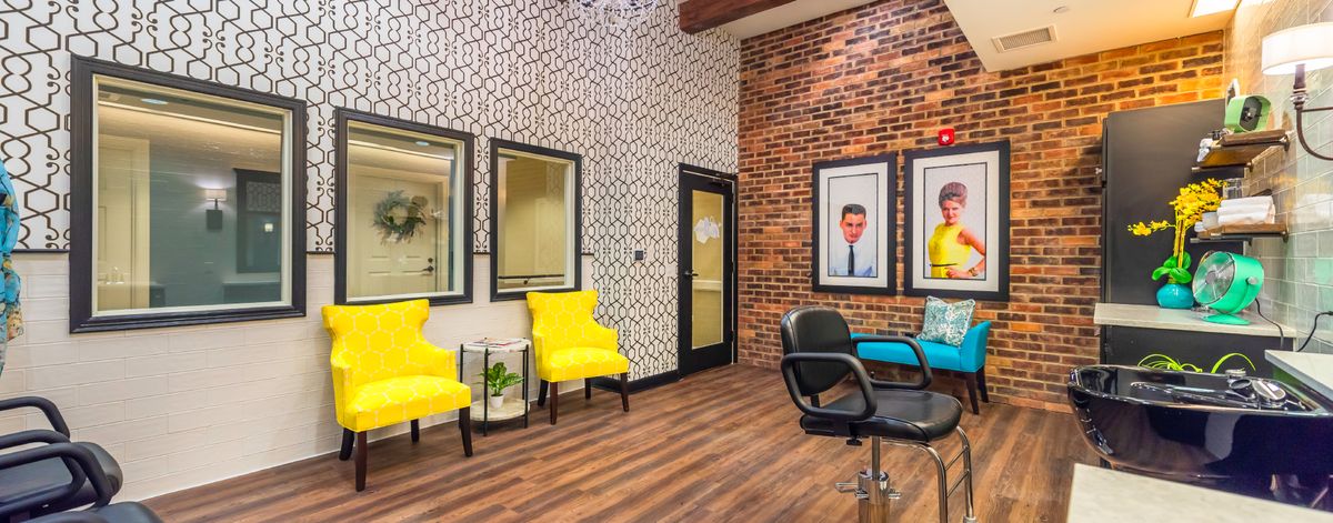 A modern salon interior featuring bright yellow chairs and textured walls.