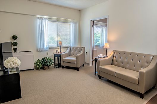 A cozy living room with comfortable seating and natural light streaming through the window.
