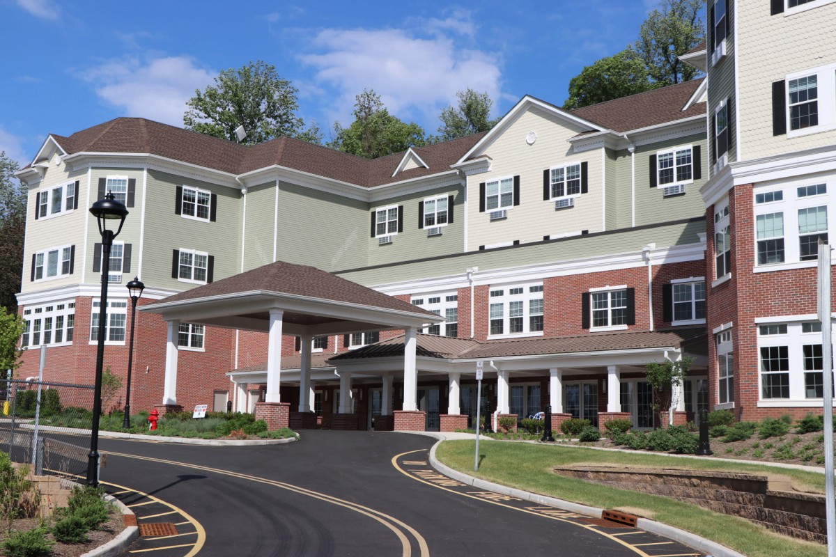 A multi-story residential building with a landscaped driveway.