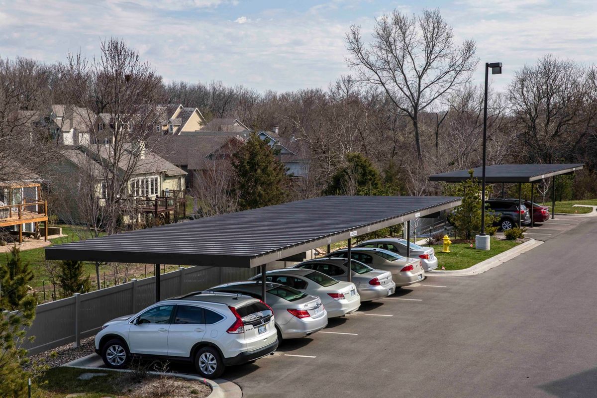 A suburban parking lot with a solar panel carport providing shade and renewable energy.