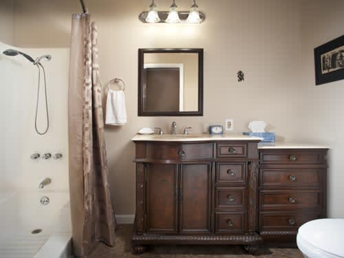 A bathroom featuring a wooden vanity with a mirror and sink, adjacent to a shower curtain.