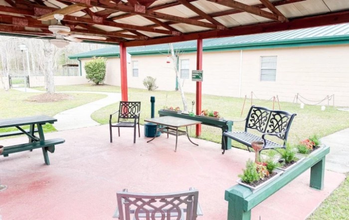 A cozy outdoor patio with chairs and plant boxes under a covered porch.