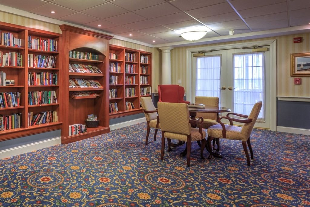 A cozy library room with bookshelves, a table, and chairs.