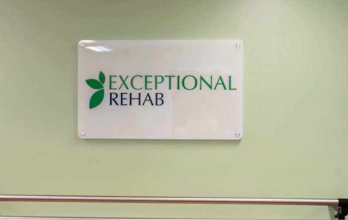 A sign on a green wall that reads 'Exceptional Rehab' indicating a rehabilitation facility.