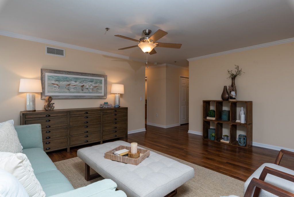 A cozy living room with a ceiling fan, artwork on the wall, and comfortable seating.
