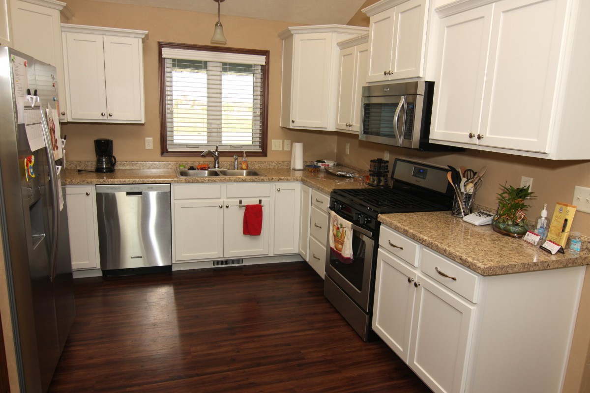 A modern kitchen with white cabinets and stainless steel appliances.