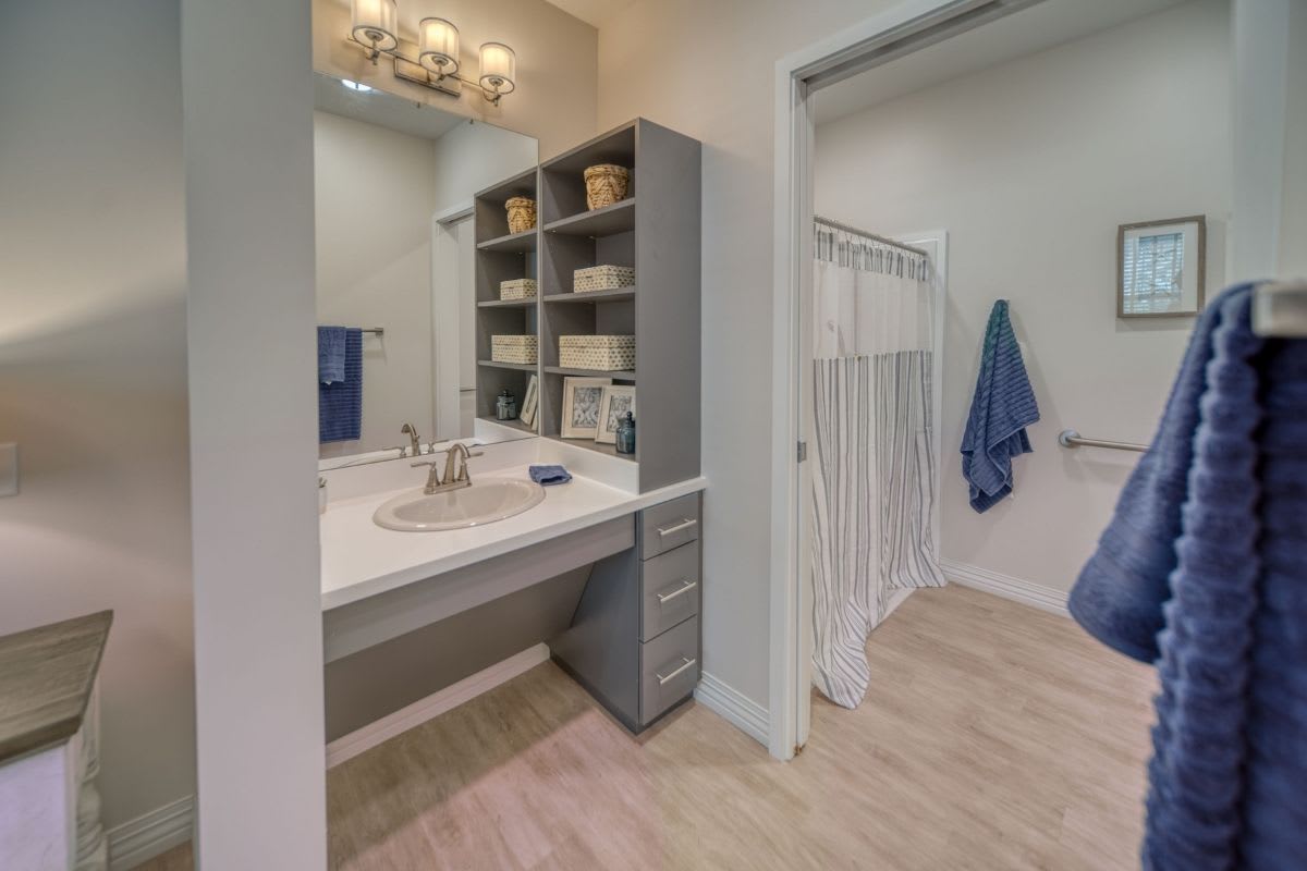A modern bathroom with a sink, mirror, and open shelving.