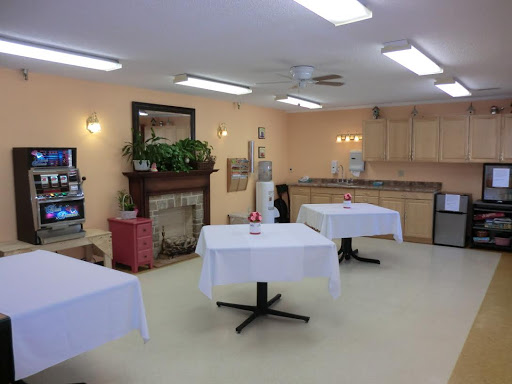 A cozy dining area featuring white tablecloths on tables and a welcoming kitchen backdrop.