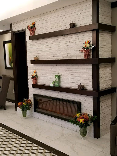 A stylish interior featuring a decorative wall with shelves and a cozy fireplace, complemented by floral arrangements.