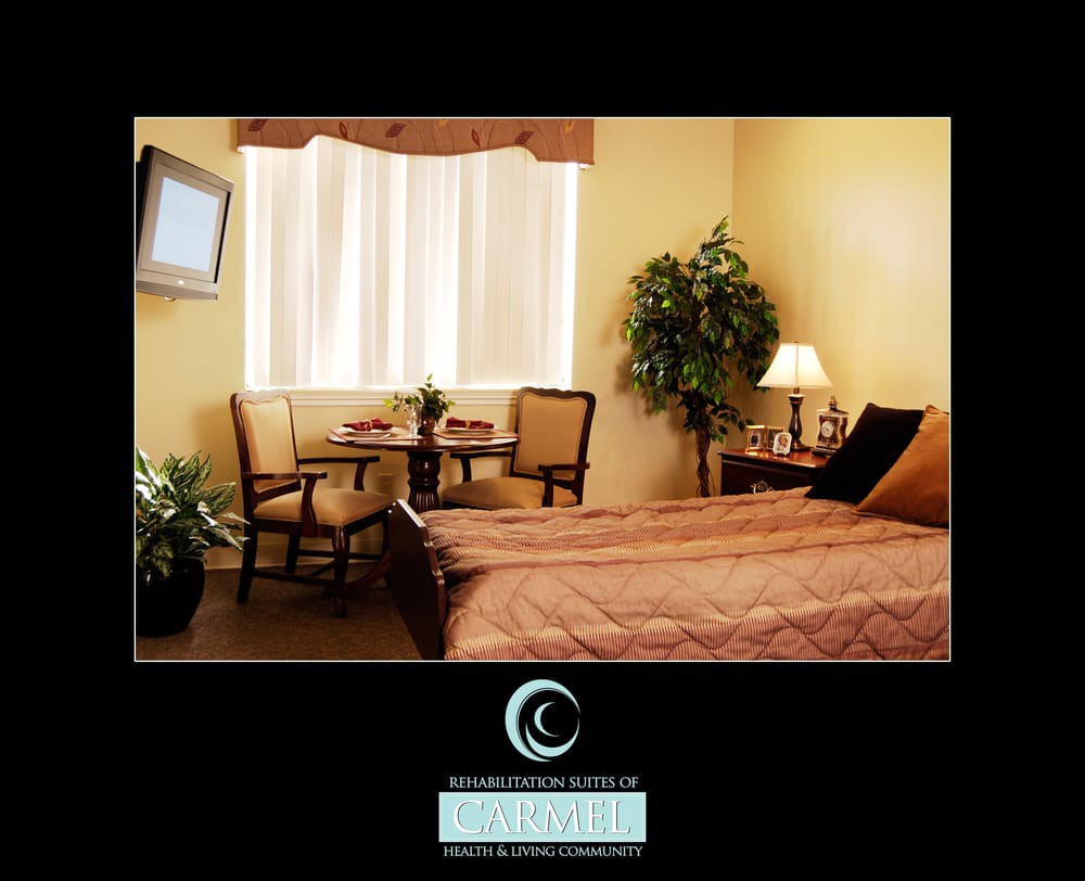 A cozy hotel room interior featuring a bed, chairs, television, and window with natural lighting.