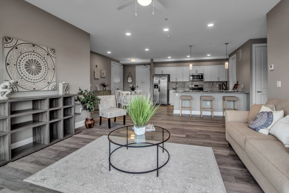 A modern open-floor-plan living room and kitchen with minimalist decor and neutral tones.