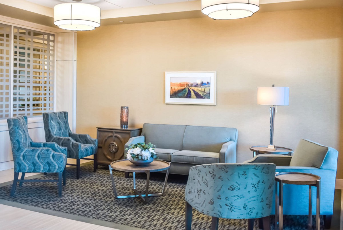 A well-decorated living room with blue chairs, a grey sofa, and a coffee table.