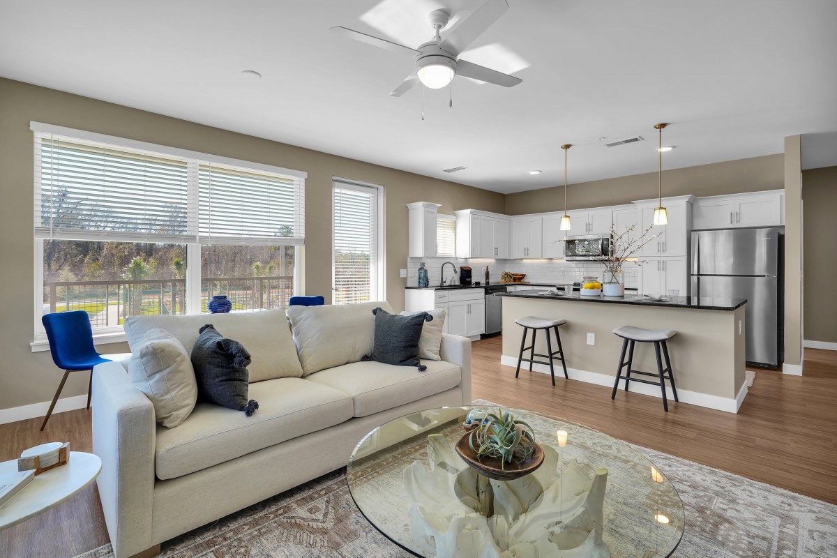 A modern open-concept living room and kitchen with ample natural light.