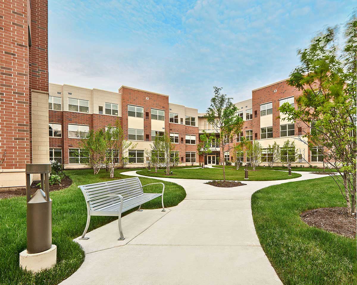 A modern building surrounded by landscaped pathways and greenery.