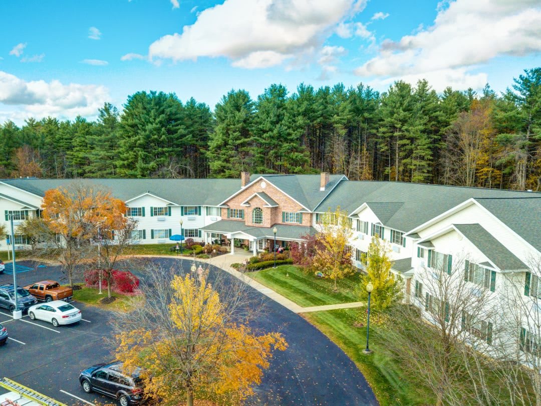 Aerial view of a building surrounded by trees and a parking lot in a natural setting.