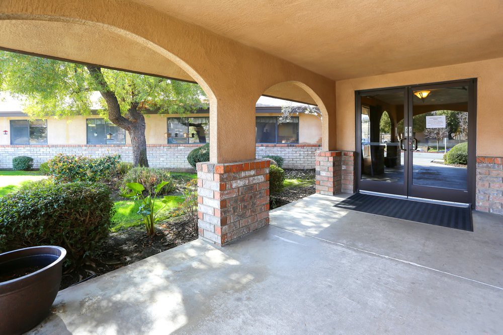 A covered entrance to a building with brick pillars and surrounding greenery.