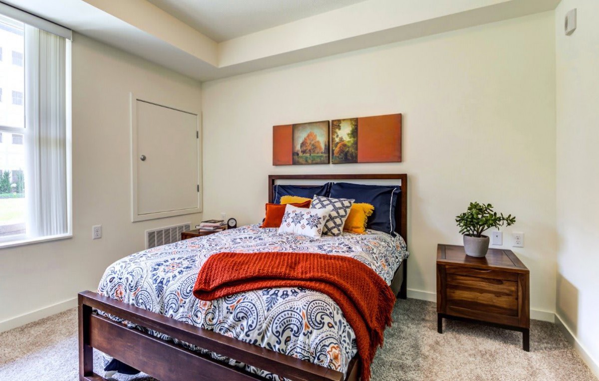 A cozy bedroom with vibrant bedding, decorative cushions, and wall art.