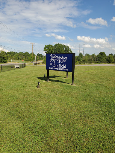A large blue sign stands in a grassy field under a partly cloudy sky.