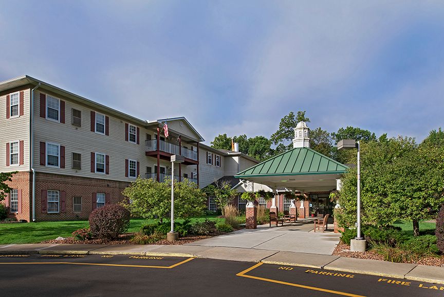An inviting entrance to a multi-story building with a green roof and well-maintained landscaping.