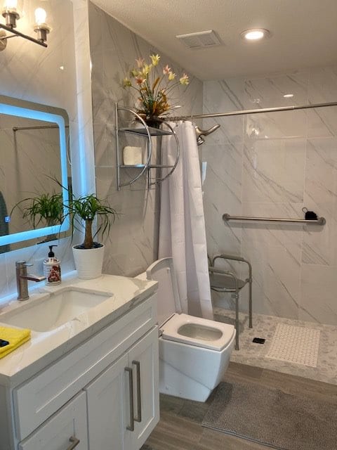 A modern bathroom with a shower, sink, and potted plants.