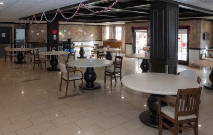 An empty restaurant interior featuring round tables and elegant chairs.