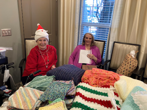 Two women enjoying a cozy crafting session surrounded by handmade blankets.