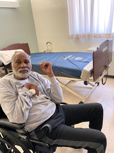 An elderly man sitting in a wheelchair in a hospital room.