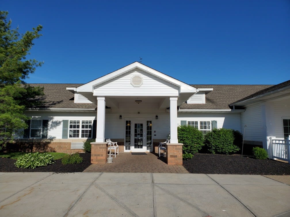 Front view of a white building with columns and a porch under a clear blue sky.