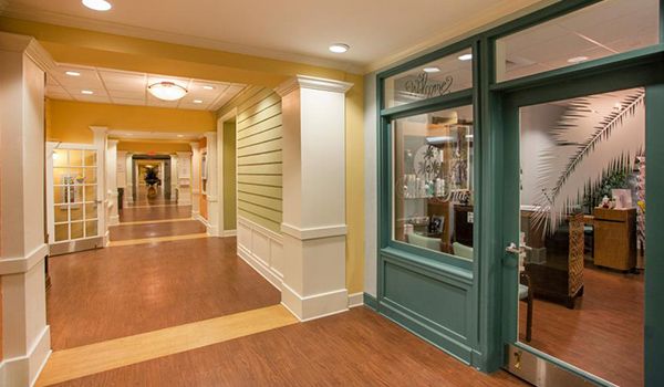 A brightly lit indoor hallway with wooden flooring, featuring green and yellow walls and a glass display.