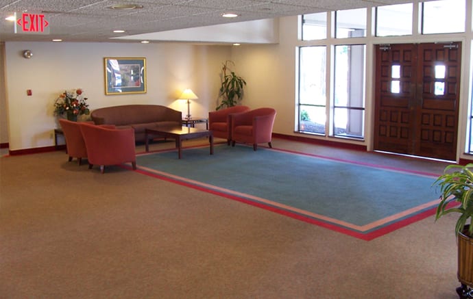 A hotel lobby with comfortable seating, including a sofa and chairs around a coffee table on a carpet.
