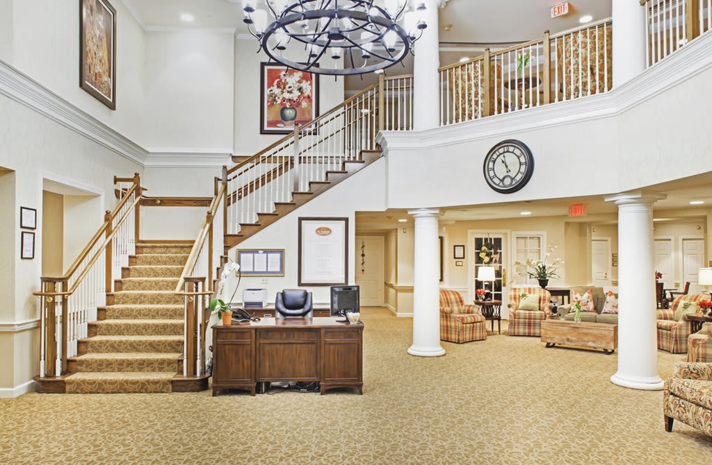 A welcoming lobby area featuring a staircase, chandelier, and reception desk.
