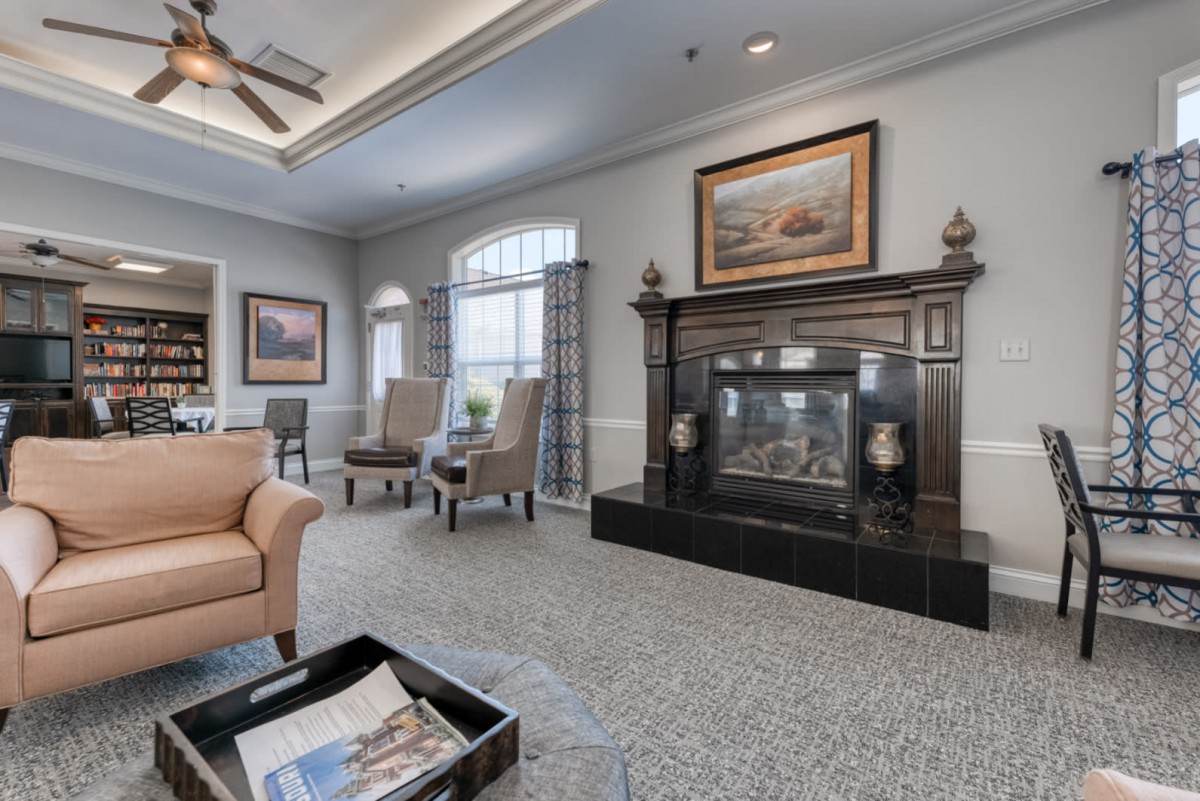 A well-decorated living room featuring a prominent fireplace, comfortable seating, and elegant artwork.