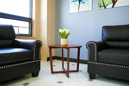 A cozy seating area featuring two black chairs, a small wooden table, and a vase of flowers.