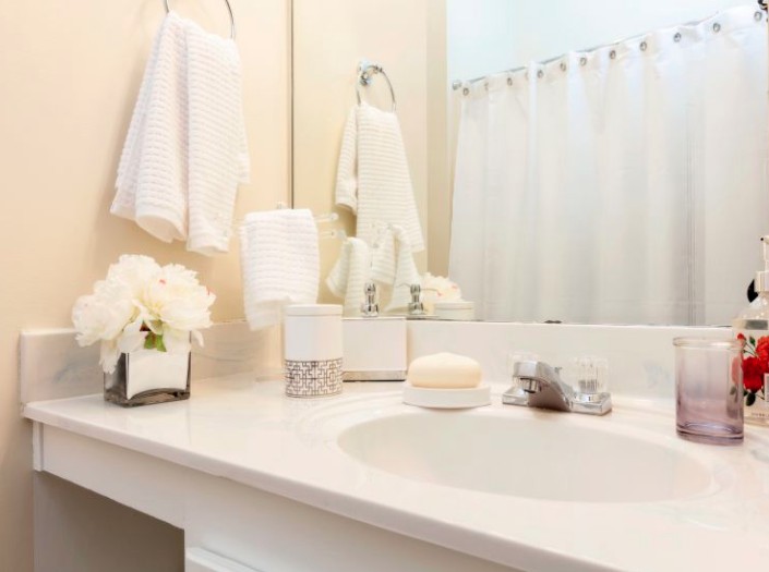 A clean and neatly organized bathroom countertop with towels, flowers, and soap.