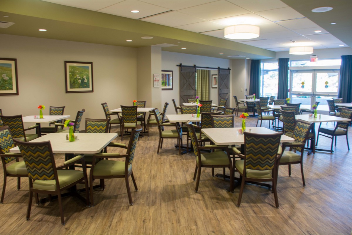 A modern dining area with neatly arranged tables and chairs on a wooden floor.